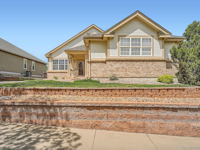 view of front of house featuring brick siding, central air condition unit, and a front lawn