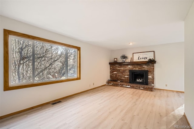 unfurnished living room featuring light hardwood / wood-style floors and a brick fireplace