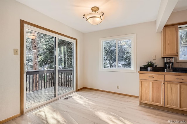 dining room with light wood-style floors, visible vents, and baseboards