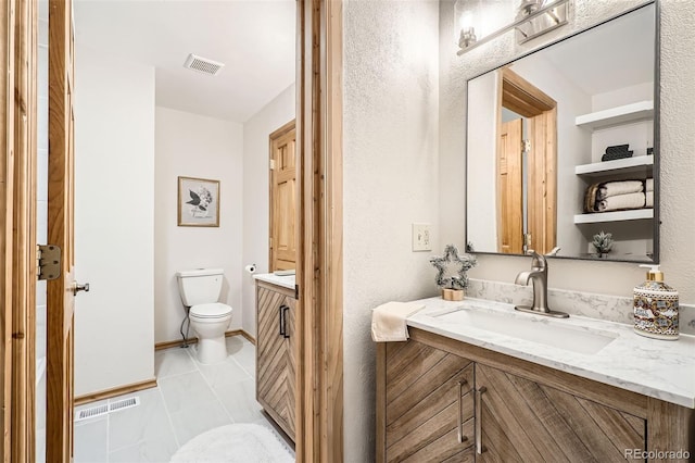 bathroom featuring toilet, vanity, visible vents, and baseboards