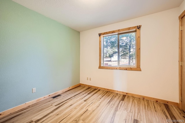 empty room with light hardwood / wood-style floors and a textured ceiling