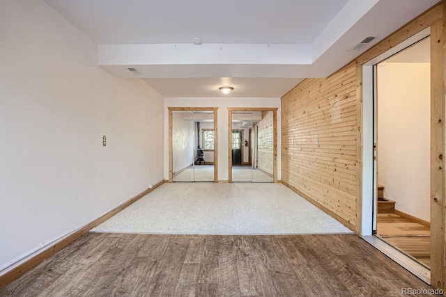 spare room with light hardwood / wood-style floors and wooden walls