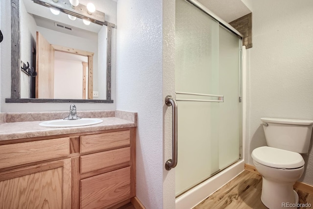 bathroom with hardwood / wood-style flooring, vanity, toilet, and an enclosed shower