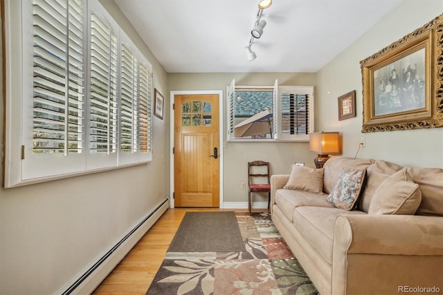 living room featuring a baseboard radiator, light wood-type flooring, and rail lighting