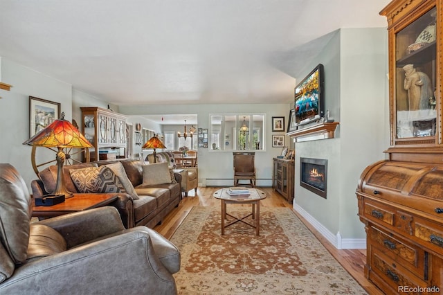 living room featuring a baseboard radiator, a chandelier, and light wood-type flooring