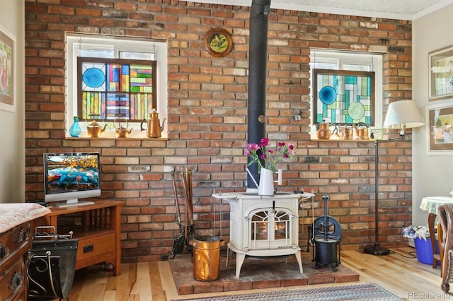 living room with crown molding, hardwood / wood-style floors, and brick wall