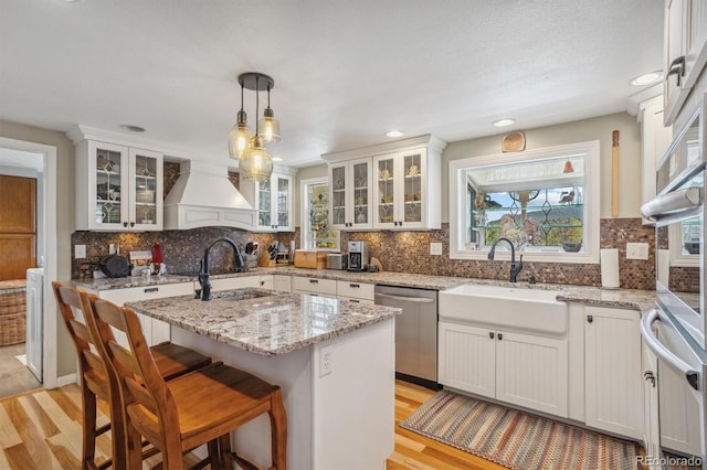 kitchen featuring appliances with stainless steel finishes, white cabinetry, a center island, and hanging light fixtures