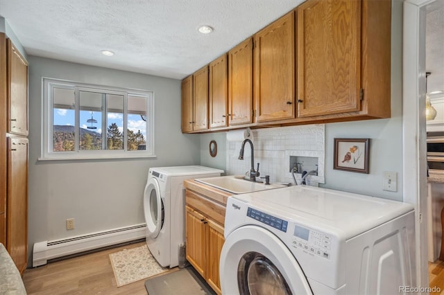 clothes washing area featuring sink, separate washer and dryer, light wood-type flooring, baseboard heating, and cabinets