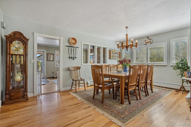 dining space featuring a textured ceiling, an inviting chandelier, light wood-type flooring, and a baseboard heating unit