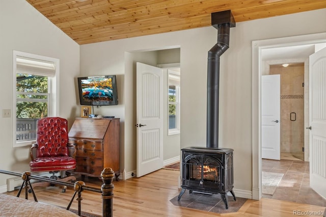 interior space with lofted ceiling, hardwood / wood-style floors, wood ceiling, and a wood stove