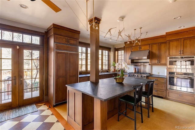 kitchen featuring french doors, light tile flooring, a center island, a breakfast bar, and appliances with stainless steel finishes