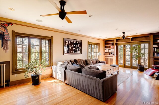 living room with ceiling fan, light hardwood / wood-style flooring, crown molding, french doors, and built in features