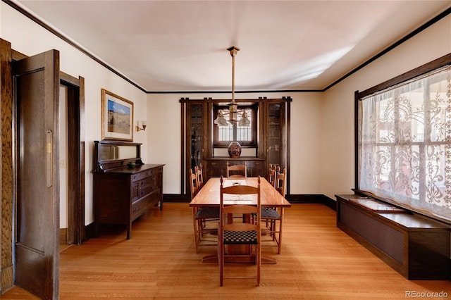 dining area with ornamental molding and light hardwood / wood-style floors