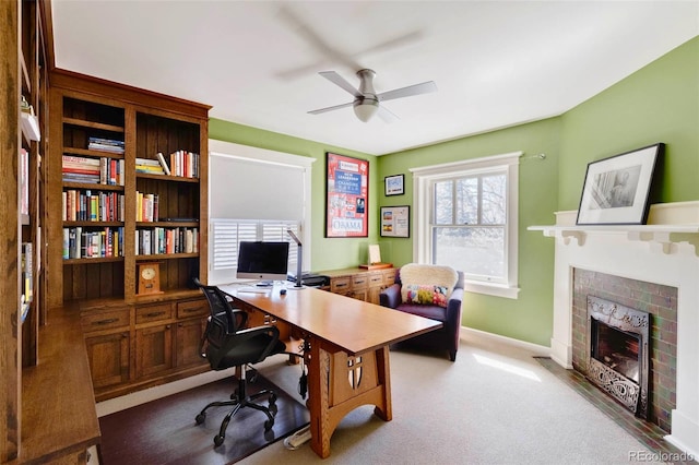 office area featuring carpet, ceiling fan, and a brick fireplace