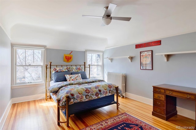 bedroom with multiple windows, ceiling fan, radiator heating unit, and light hardwood / wood-style flooring