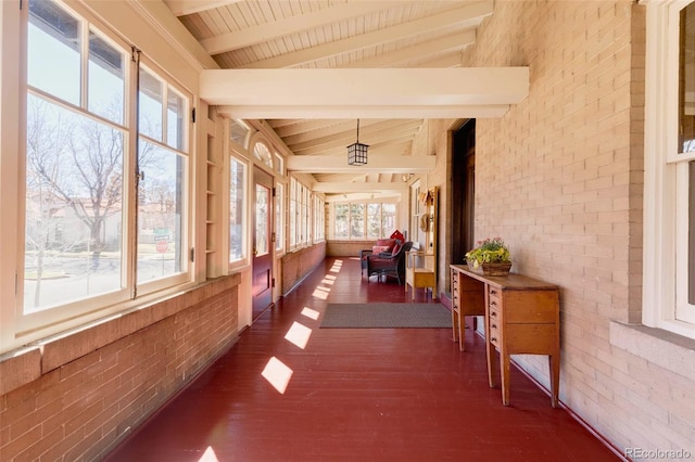 sunroom / solarium featuring vaulted ceiling with beams