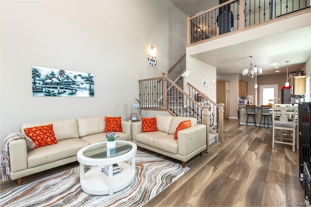 living room with dark wood-type flooring, an inviting chandelier, and a high ceiling