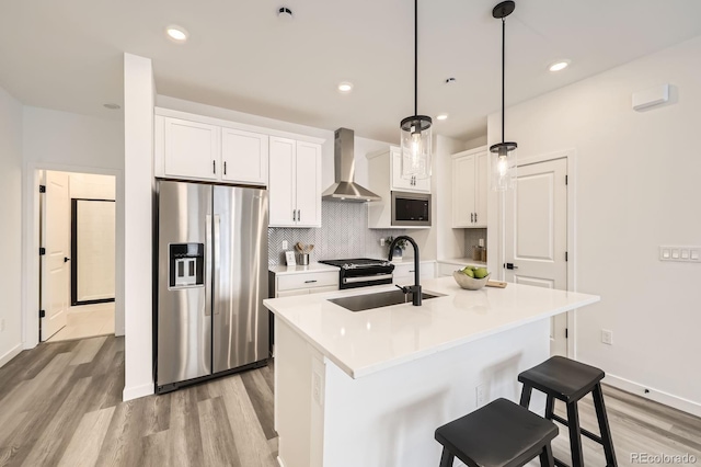 348 N Geneva St, Aurora, CO 80010 - kitchen with appliances with stainless steel finishes, wall chimney exhaust hood, a sink, light wood finished floors, and white cabinetry