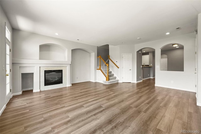 280 Granby Way Unit C, Aurora, CO 80011 - unfurnished living room featuring recessed lighting, stairs, wood finished floors, a glass covered fireplace, and arched walkways