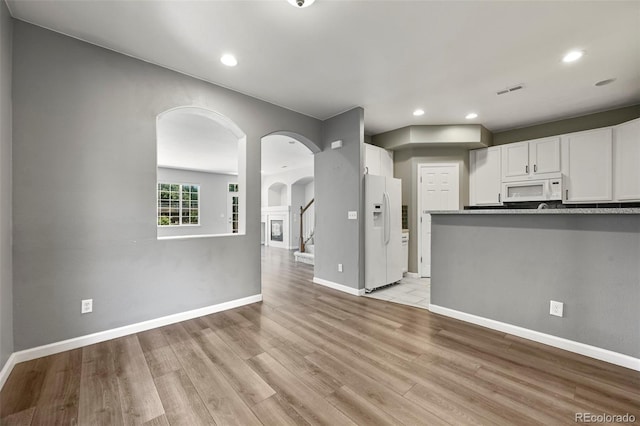 280 Granby Way Unit C, Aurora, CO 80011 - kitchen with white appliances, arched walkways, white cabinets, light wood-type flooring, and recessed lighting