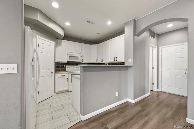 280 Granby Way Unit C, Aurora, CO 80011 - kitchen featuring white appliances, arched walkways, light wood-type flooring, white cabinetry, and decorative backsplash