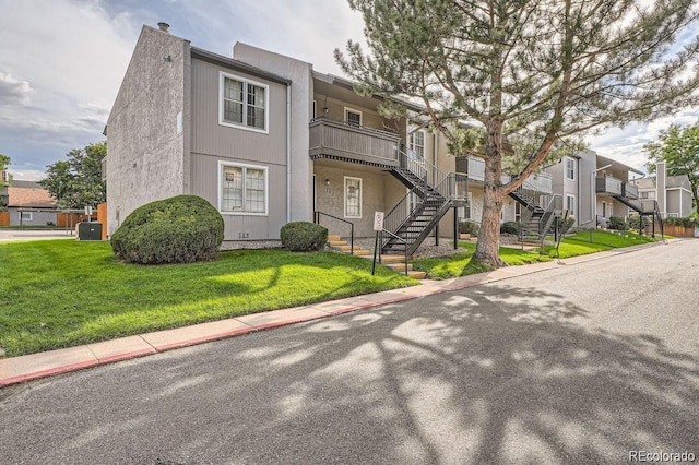 exterior space featuring stairs, a front yard, a residential view, and central air condition unit