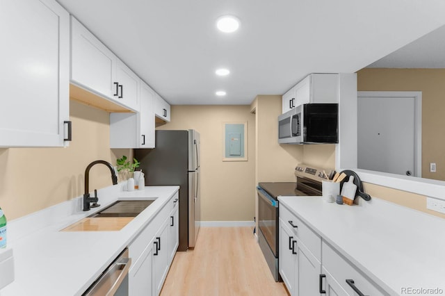 kitchen with stainless steel appliances, a sink, light wood-type flooring, white cabinets, and recessed lighting