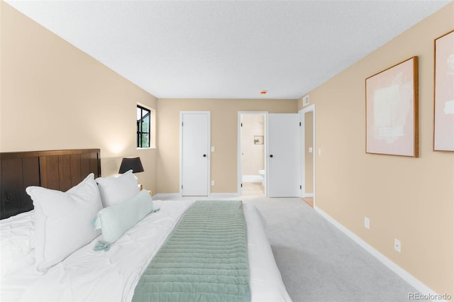 bedroom with baseboards, light carpet, and connected bathroom