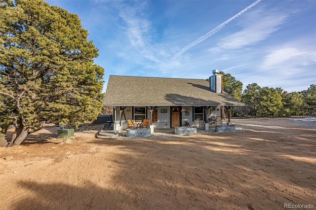 view of front facade with covered porch, a chimney, and a shingled roof