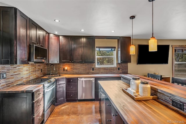 kitchen featuring butcher block countertops, appliances with stainless steel finishes, decorative light fixtures, dark brown cabinets, and sink