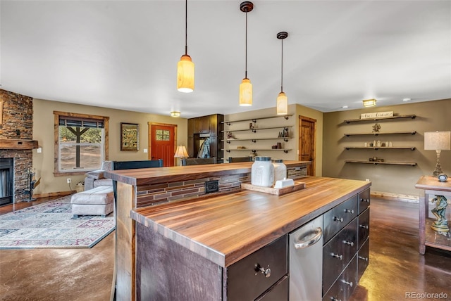 kitchen with a fireplace, a center island, dark brown cabinetry, hanging light fixtures, and wood counters