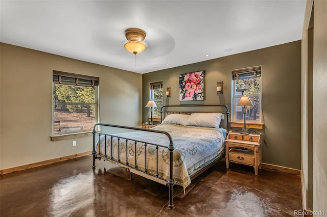 bedroom featuring finished concrete flooring, baseboards, and ceiling fan