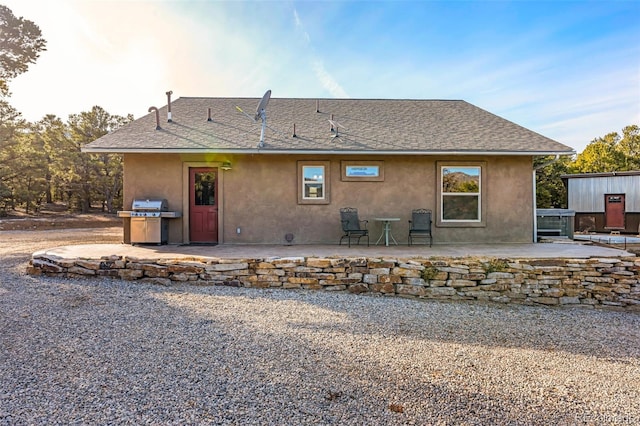 rear view of property featuring a patio area, stucco siding, and a shingled roof