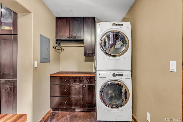 clothes washing area featuring cabinets, electric panel, and stacked washer and dryer