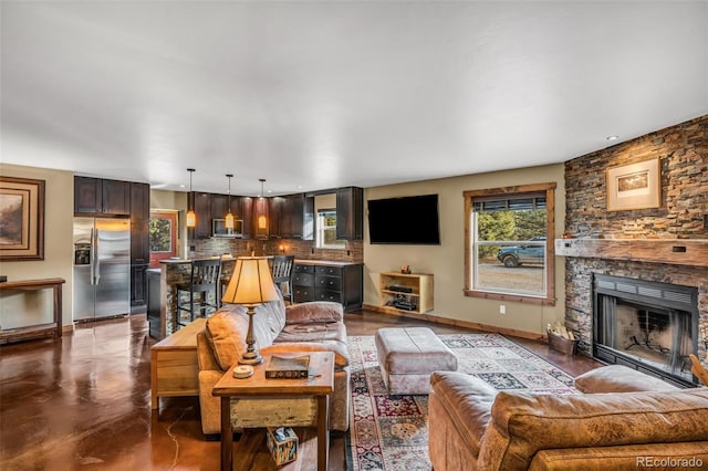 living room featuring baseboards and a stone fireplace