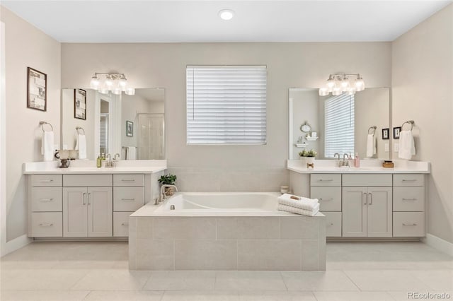 bathroom featuring two vanities, a sink, a shower stall, and a bath