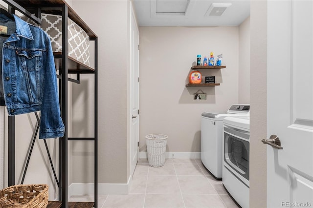 laundry area with laundry area, light tile patterned flooring, washing machine and clothes dryer, and baseboards