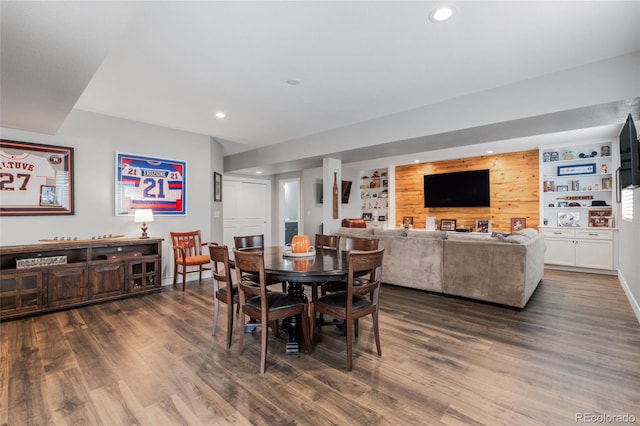 dining space with built in shelves, wooden walls, and dark hardwood / wood-style floors