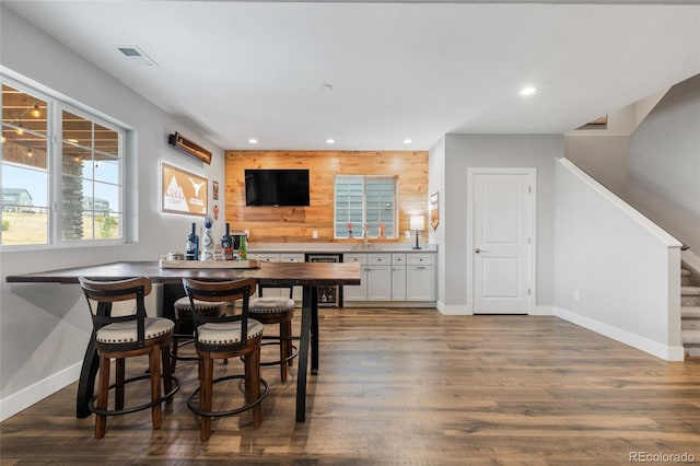 interior space featuring dark hardwood / wood-style floors, beverage cooler, and wood walls