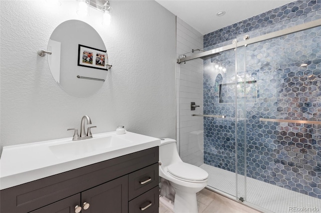 bathroom with a shower with door, vanity, tile patterned floors, and toilet