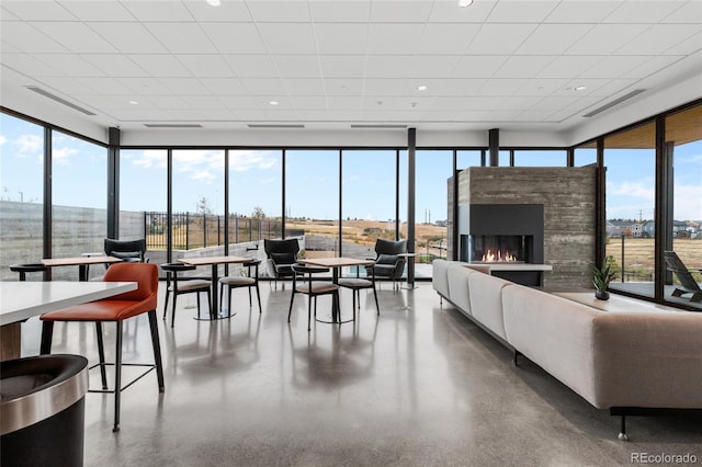 interior space featuring a glass covered fireplace, visible vents, and floor to ceiling windows