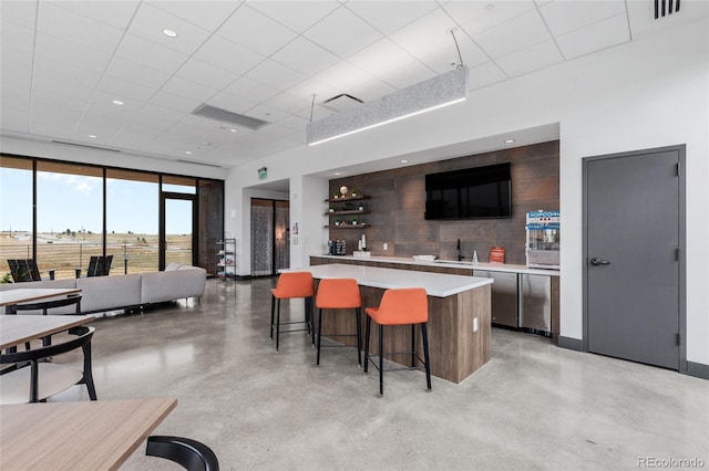 kitchen featuring a kitchen island, finished concrete flooring, light countertops, tasteful backsplash, and modern cabinets