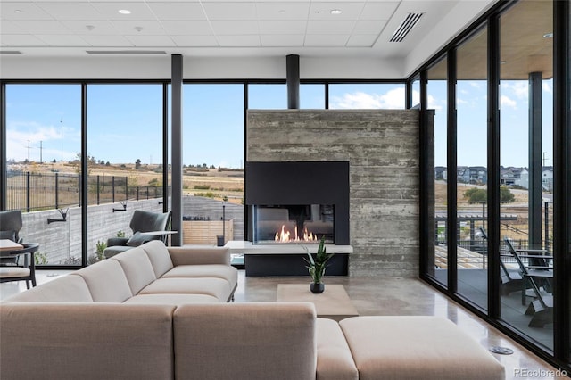 living room with a healthy amount of sunlight, a drop ceiling, a fireplace, and a wall of windows