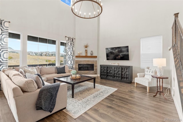 living area featuring baseboards, a fireplace, wood finished floors, and an inviting chandelier