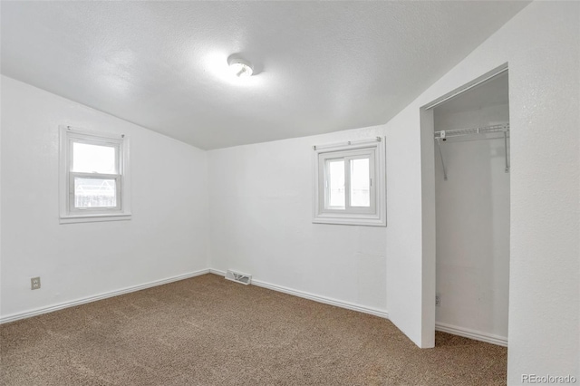 interior space with vaulted ceiling, carpet flooring, a textured ceiling, and a closet