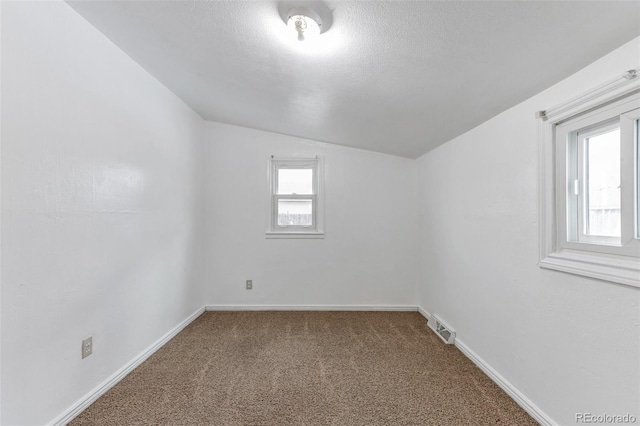 unfurnished room with lofted ceiling, a textured ceiling, and carpet flooring