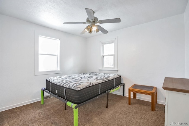 bedroom with ceiling fan, carpet floors, and a textured ceiling