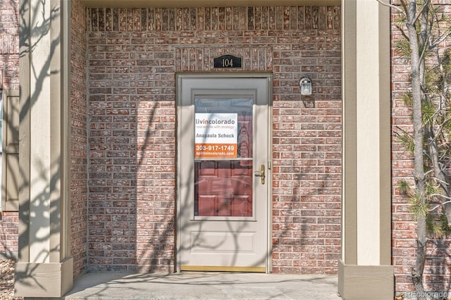 view of exterior entry featuring brick siding