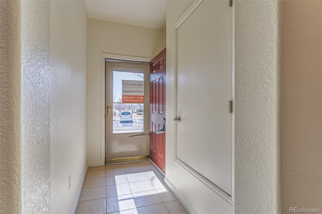 entryway with a textured wall, baseboards, and light tile patterned floors