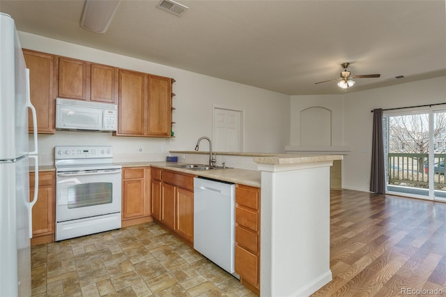 kitchen with light countertops, visible vents, a sink, white appliances, and a peninsula